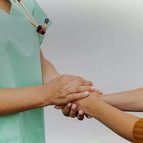 A nurse gently holding a patient's hands