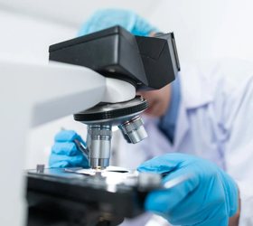 A lab specialist looking through a microscope