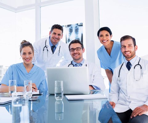 A smiling team of doctors and nurses gathered around a table
