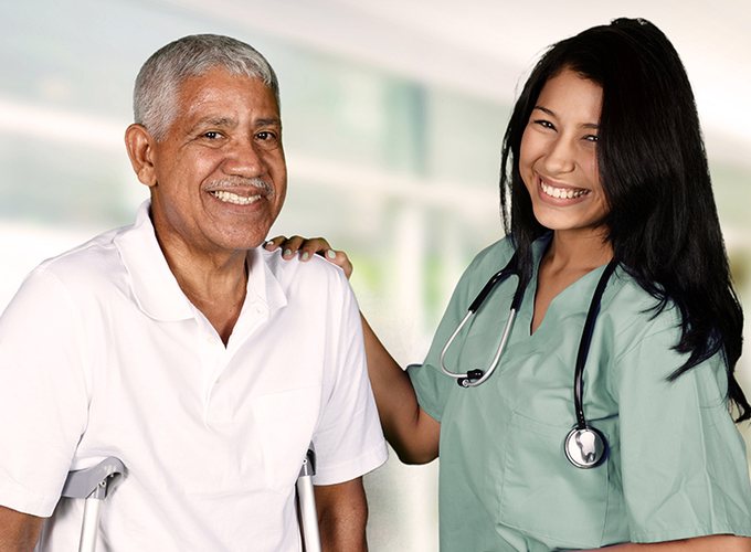 A smiling nurse with her hand on the shoulder of a happy senior patient