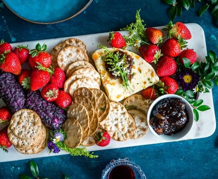 A platter of fresh strawberries, crackers and healthy snacks