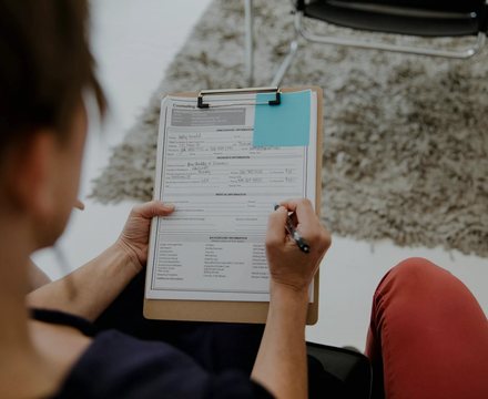 A patient filling in a form on a clipboard