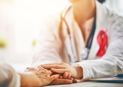 A doctor holding a patient's hand during a caring consultation