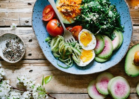 A healthy bowl of greens, eggs, avocado and radish