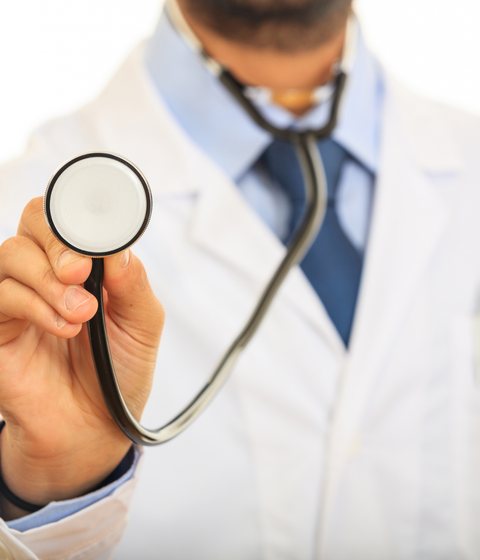 A doctor in a white coat holding out a stethoscope